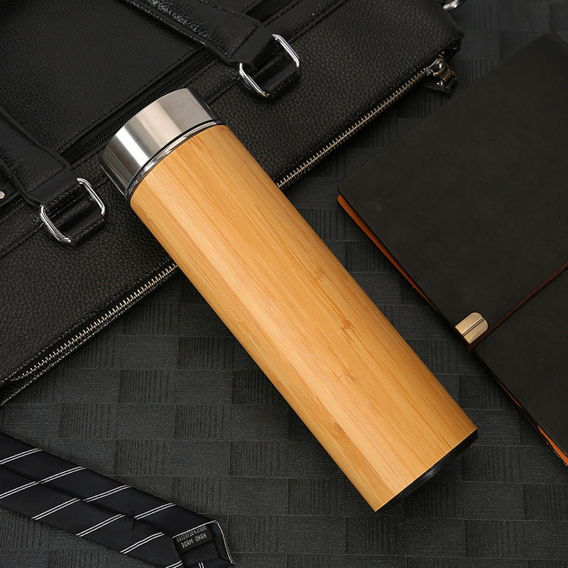 Wooden tumbler with black briefcase and notebook on a dark textured surface