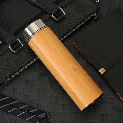 Wooden tumbler with black briefcase and notebook on a dark textured surface